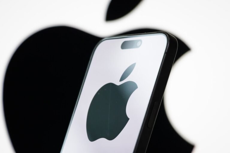 In this photo illustration, the logo of Apple Inc. is displayed on a smartphone screen, with the company's iconic black apple symbol visible in the background.