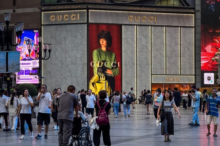 People walk past a Gucci store with a large advertisement displayed on its exterior at the Jiefangbei central business district on September 9, 2025, in Chongqing, China.