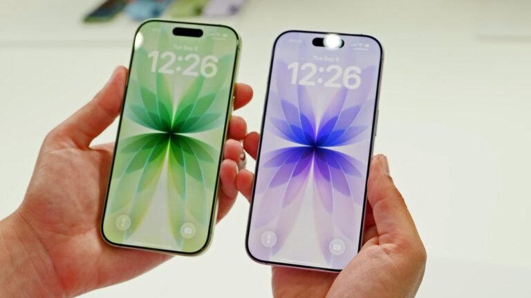 Two iPhone 17 phones, one green and one purple, being held in a pair of hands against a light background.
