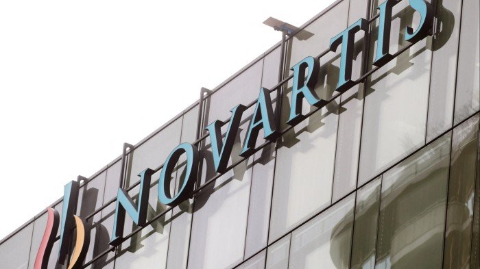 Big pharma’s scramble over the patent cliff will be costly Novartis logo displayed on the exterior of a glass office building.