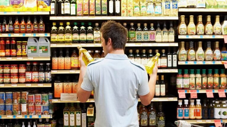 You’re About to Ruin Thanksgiving Dinner With the Wrong Cooking Oil man holding bottles of oil in supermarket aisle